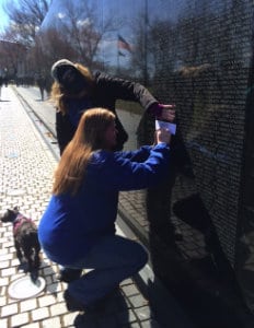Woman etching name from Vietnam Memorial