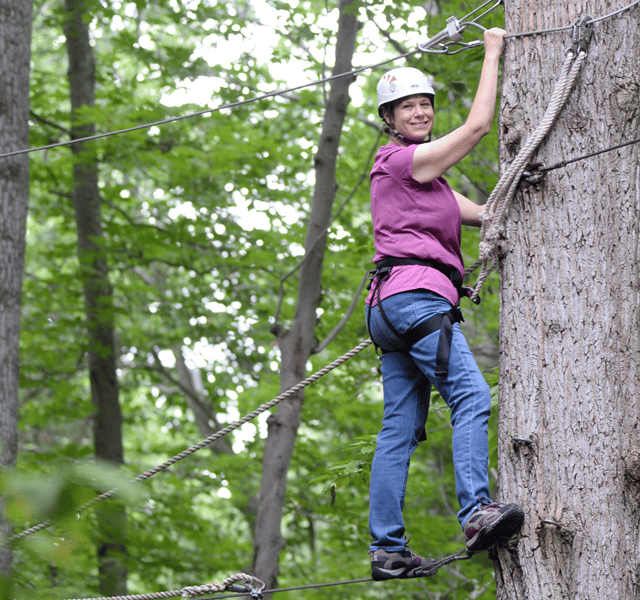 Women Climbing tree while in safety harness
