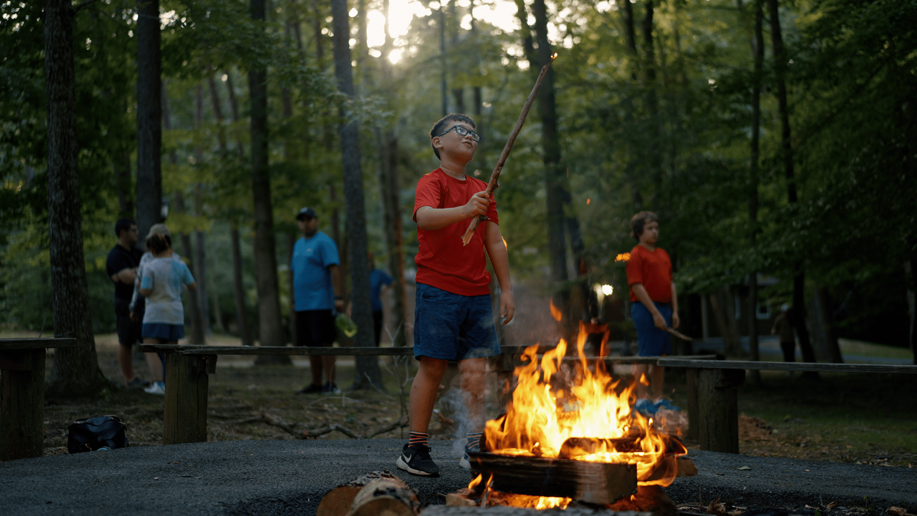 Boy playing with stick at camp fire