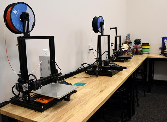 Square photo with 3D printers on work bench