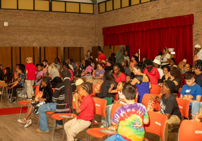 Group of YES students in an auditorium at Apple Grove Elementary, most of them seated but some standing