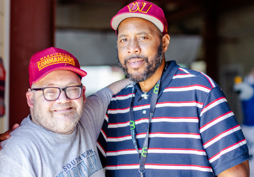 David Moore (left) and Thomas Robinson (right), both in maroon ballcaps, with arm around each other