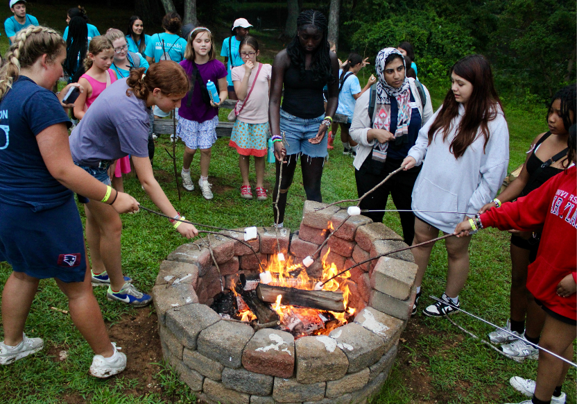 A group of campers roasting marshmallows over a fire